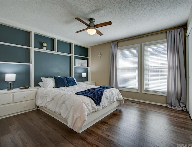 bedroom with ceiling fan, dark hardwood / wood-style flooring, and a textured ceiling