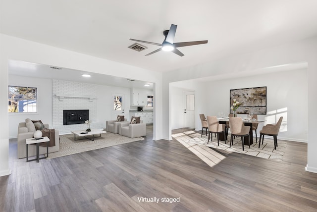 living room featuring a fireplace, wood-type flooring, and ceiling fan