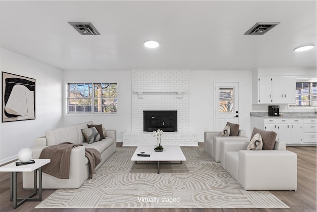 living room featuring a brick fireplace and light wood-type flooring