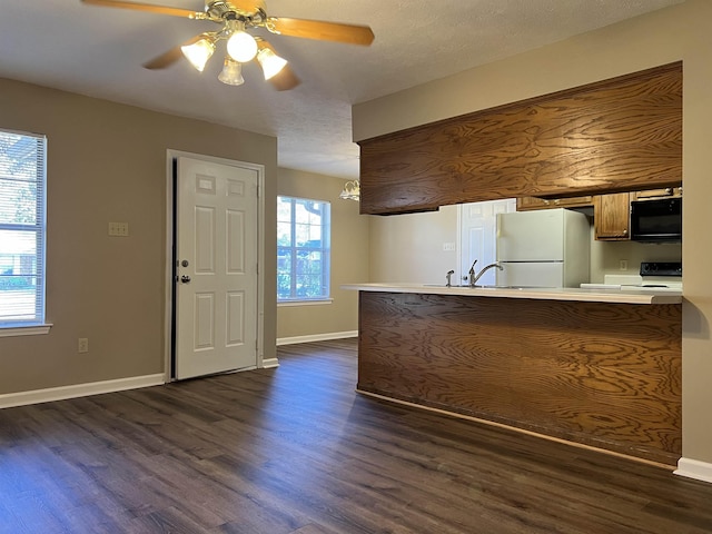 kitchen featuring white refrigerator, range, ceiling fan, kitchen peninsula, and dark wood-type flooring