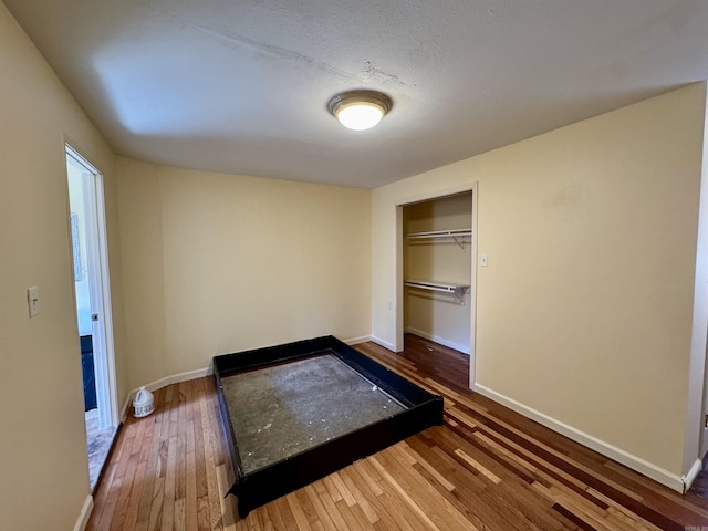 unfurnished bedroom featuring hardwood / wood-style floors, a textured ceiling, and a closet