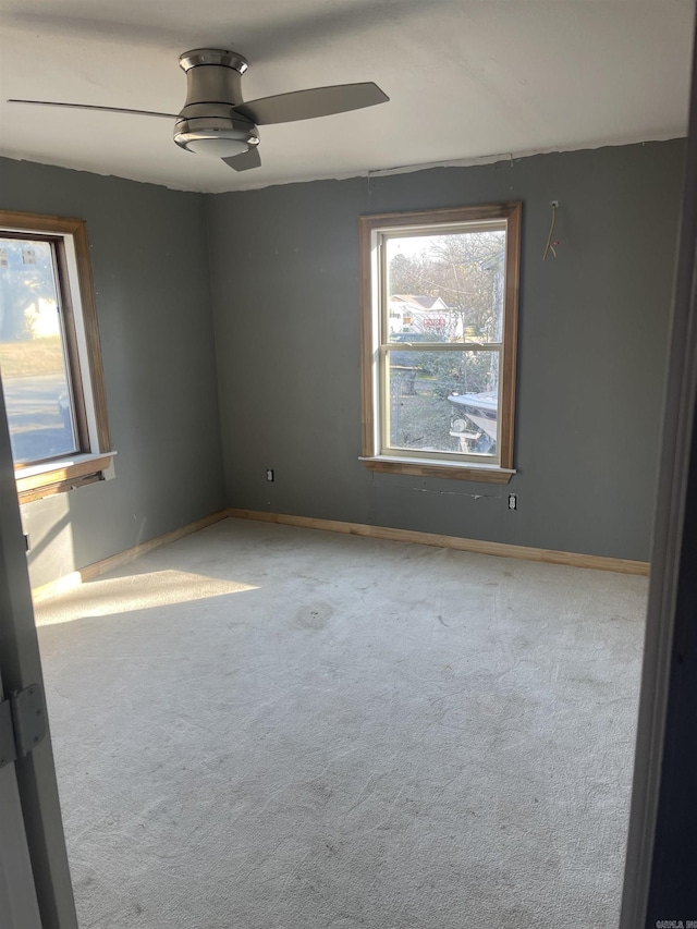 unfurnished room featuring ceiling fan, light colored carpet, and plenty of natural light