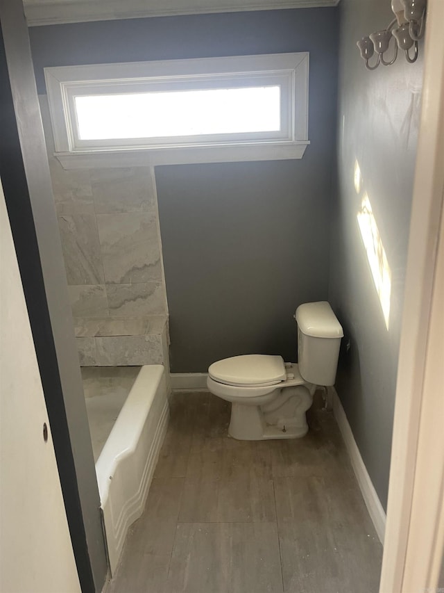 bathroom featuring a bath, hardwood / wood-style floors, and toilet