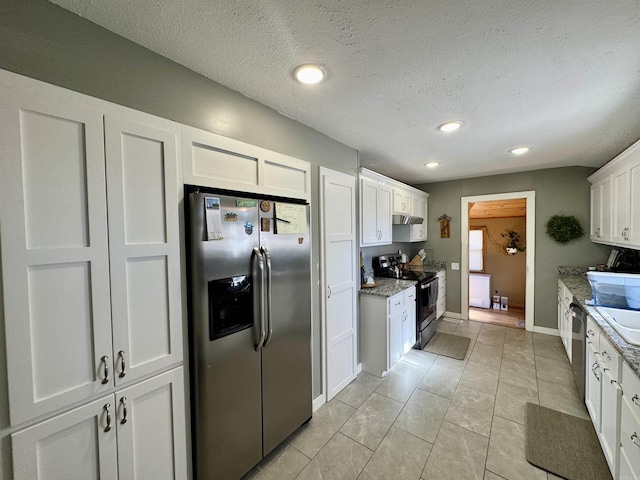 kitchen featuring appliances with stainless steel finishes, white cabinets, light tile patterned floors, light stone countertops, and a textured ceiling