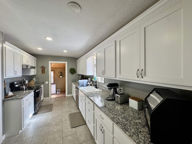 kitchen featuring light tile patterned floors, sink, appliances with stainless steel finishes, white cabinetry, and light stone counters