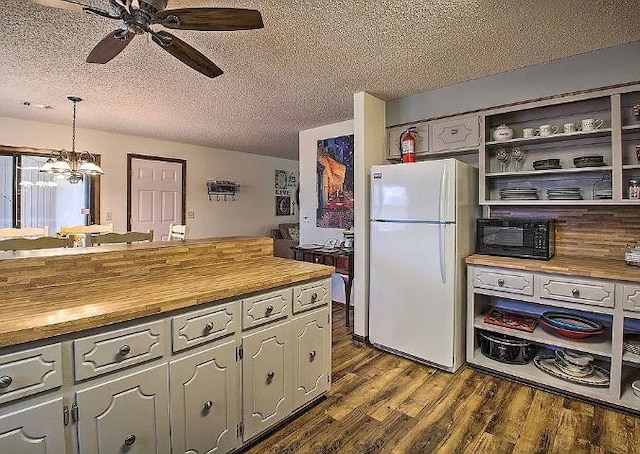 kitchen with butcher block counters, pendant lighting, a textured ceiling, and white fridge