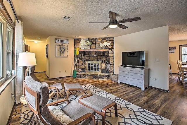 living room with hardwood / wood-style flooring, ceiling fan, a textured ceiling, and a fireplace