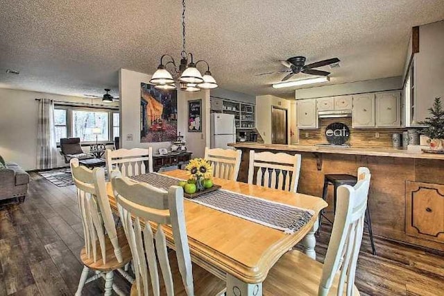 dining space featuring dark hardwood / wood-style floors, ceiling fan with notable chandelier, and a textured ceiling