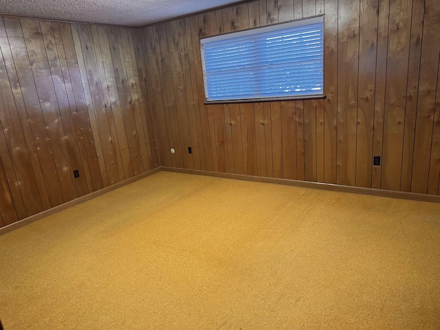 unfurnished room with carpet flooring, wooden walls, and a textured ceiling