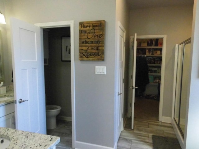 bathroom featuring vanity, a shower with shower door, and toilet