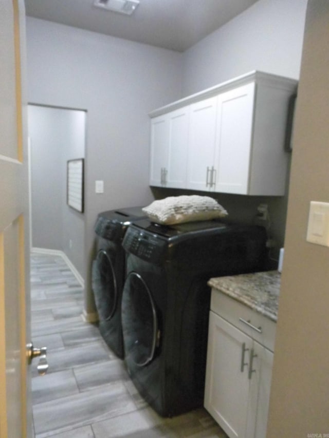 clothes washing area featuring cabinets, independent washer and dryer, and light hardwood / wood-style flooring