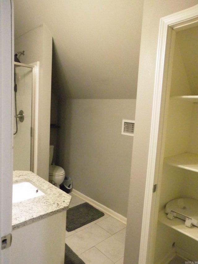 bathroom with tile patterned floors, toilet, a shower with shower door, vaulted ceiling, and vanity