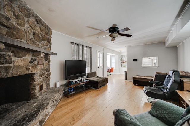 living room with ceiling fan, wood-type flooring, a stone fireplace, and plenty of natural light