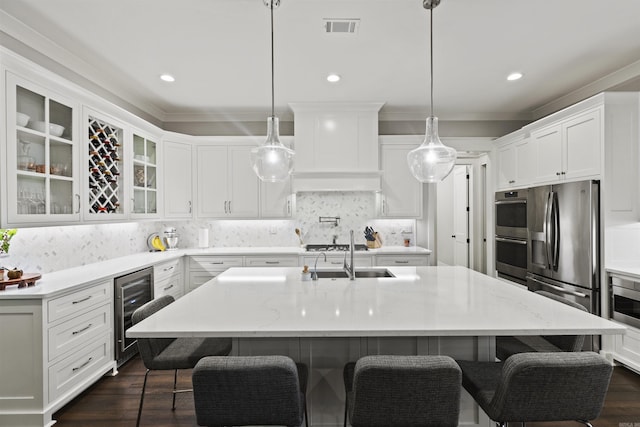 kitchen featuring tasteful backsplash, hanging light fixtures, a center island with sink, and a kitchen bar