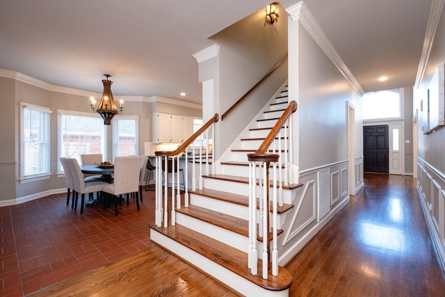 stairway featuring crown molding and a notable chandelier