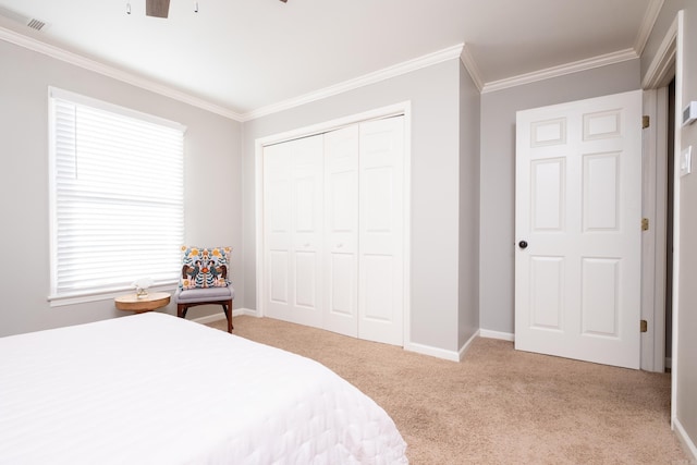 bedroom featuring ornamental molding, light colored carpet, ceiling fan, and a closet