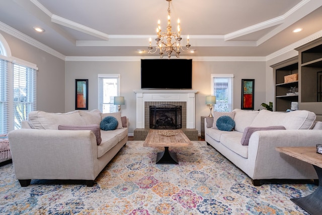 living room featuring a brick fireplace, crown molding, a wealth of natural light, and a chandelier