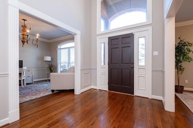 entrance foyer with a notable chandelier, ornamental molding, and dark hardwood / wood-style floors