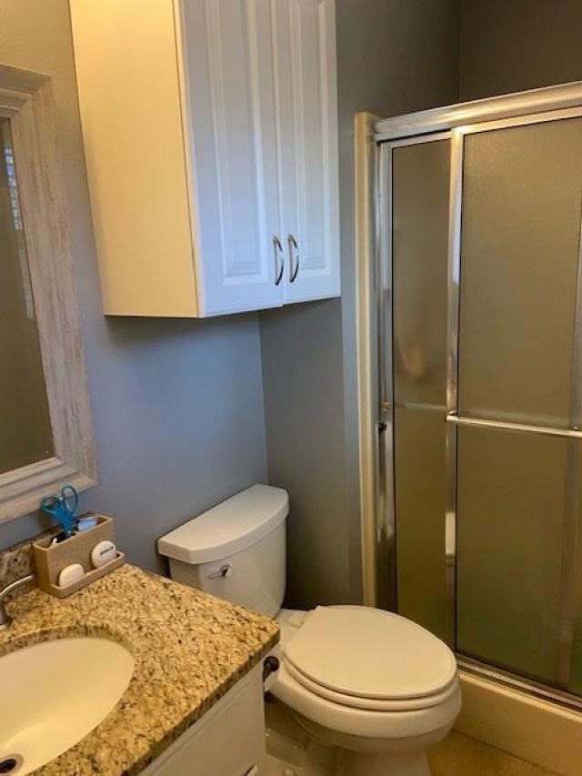 bathroom featuring vanity, walk in shower, and toilet