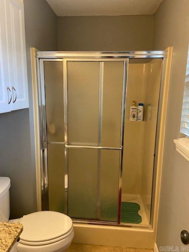 bathroom featuring vanity, toilet, a shower with shower door, and tile patterned flooring