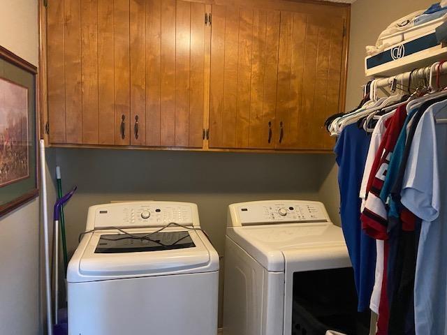 clothes washing area featuring cabinets and washer and dryer