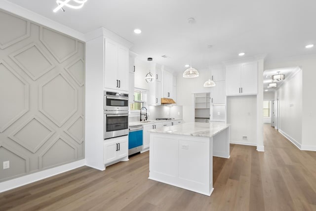 kitchen featuring a kitchen island, appliances with stainless steel finishes, decorative light fixtures, sink, and white cabinets