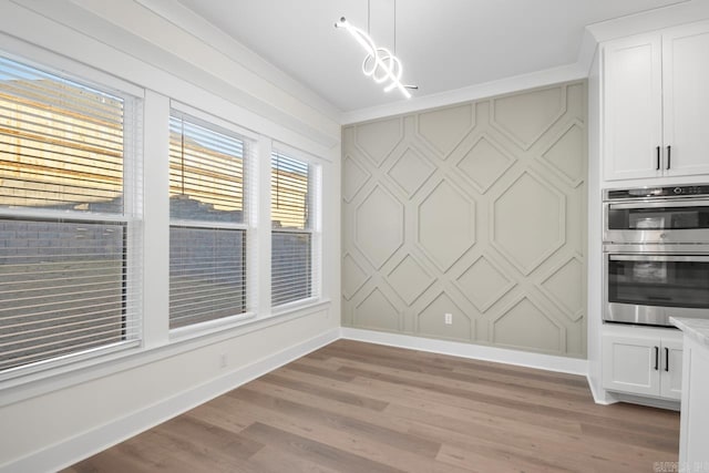 unfurnished dining area with crown molding and light wood-type flooring