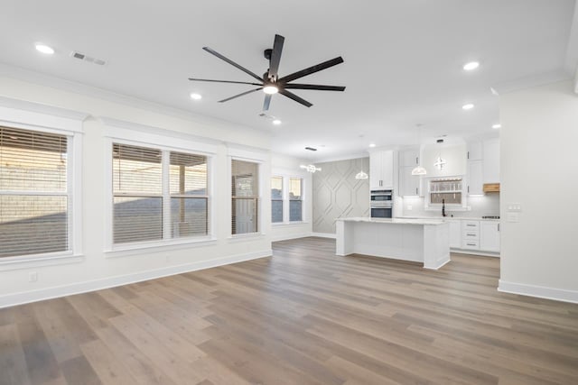 unfurnished living room with crown molding, sink, ceiling fan, and light hardwood / wood-style flooring