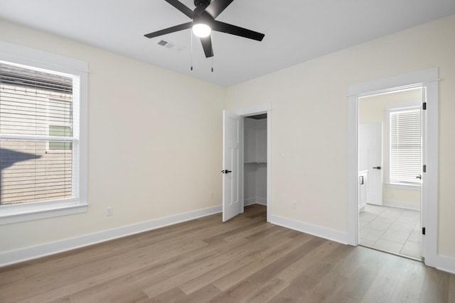 unfurnished bedroom with ceiling fan, ensuite bathroom, and light wood-type flooring