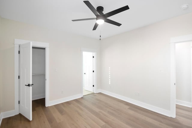 unfurnished bedroom featuring a walk in closet, light hardwood / wood-style floors, a closet, and ceiling fan