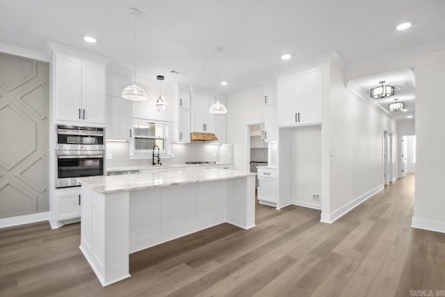 kitchen featuring double oven, white cabinetry, backsplash, a center island, and light stone countertops