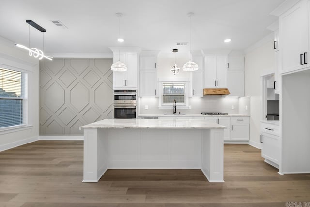 kitchen featuring white cabinetry, a kitchen island, sink, and decorative light fixtures