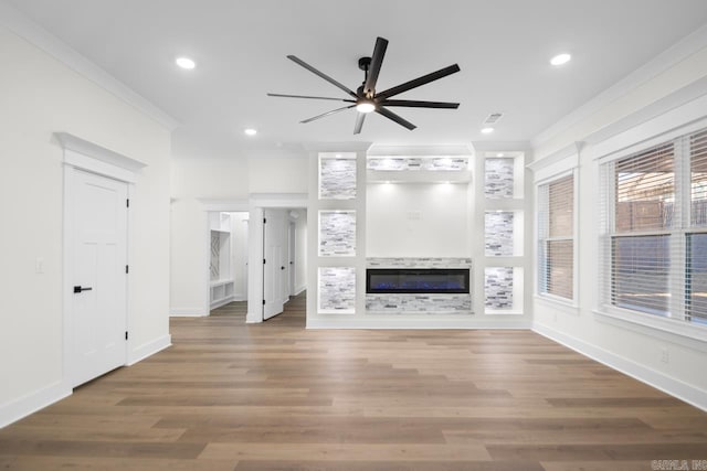 unfurnished living room with ceiling fan, hardwood / wood-style flooring, ornamental molding, and built in shelves