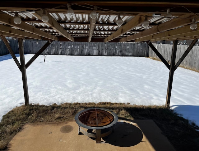 snow covered patio with a pergola and an outdoor fire pit