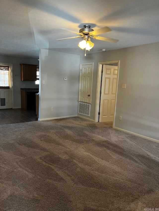 unfurnished living room featuring ceiling fan and dark carpet