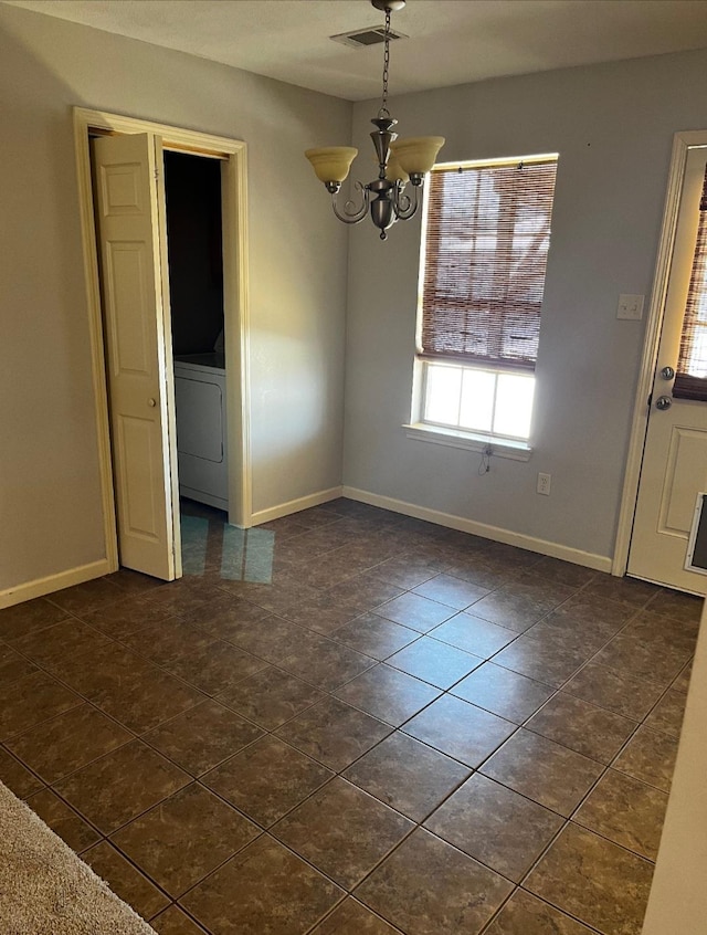 unfurnished dining area with washer / clothes dryer, a chandelier, and dark tile patterned flooring