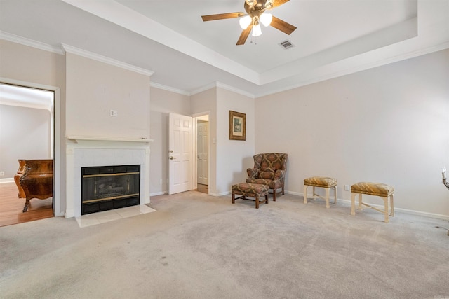 unfurnished room featuring a tile fireplace, light carpet, ceiling fan, and a tray ceiling