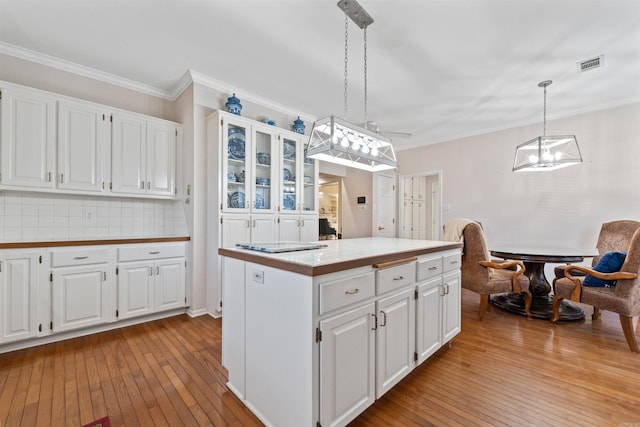 kitchen featuring hanging light fixtures, backsplash, a center island, and white cabinets