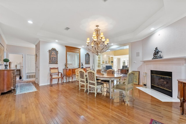 dining area featuring a fireplace, a chandelier, and light wood-type flooring