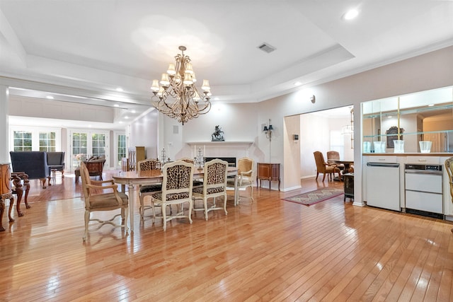 dining space featuring a chandelier, light wood-type flooring, and a tray ceiling