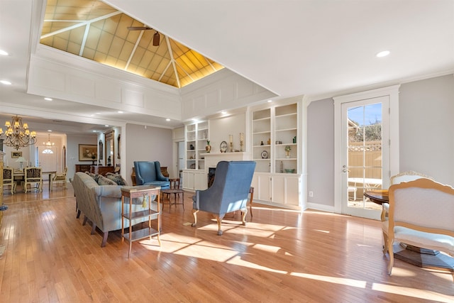 living room featuring built in shelves, a chandelier, and light wood-type flooring