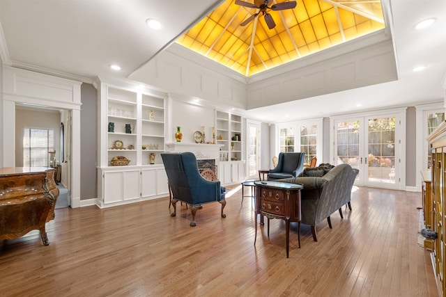 sitting room with built in shelves, ceiling fan, french doors, and hardwood / wood-style flooring