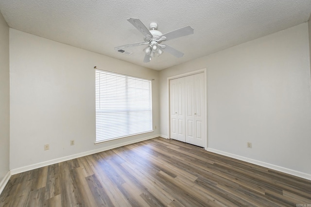 unfurnished bedroom featuring ceiling fan, dark hardwood / wood-style floors, a closet, and a textured ceiling