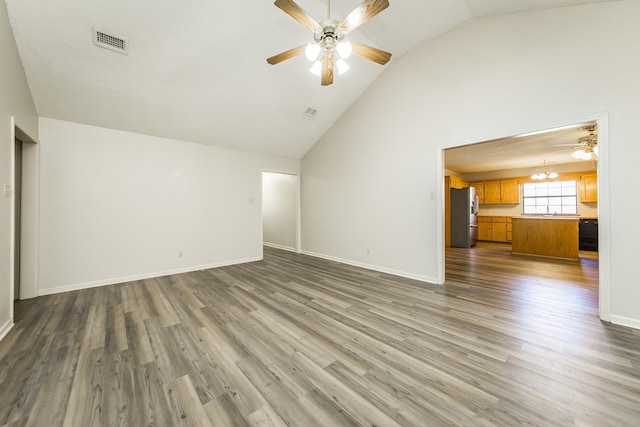 unfurnished living room featuring ceiling fan with notable chandelier and dark hardwood / wood-style flooring