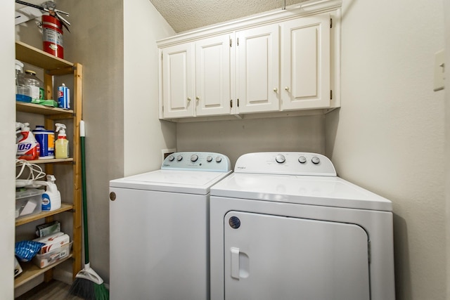 clothes washing area featuring washer and clothes dryer, cabinets, and a textured ceiling