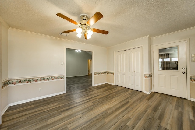 spare room featuring dark hardwood / wood-style flooring, ceiling fan, ornamental molding, and a textured ceiling