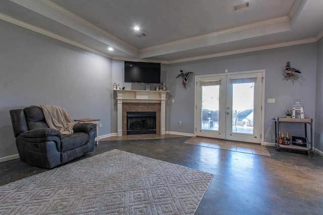 living room with french doors, ornamental molding, a tray ceiling, and a tiled fireplace