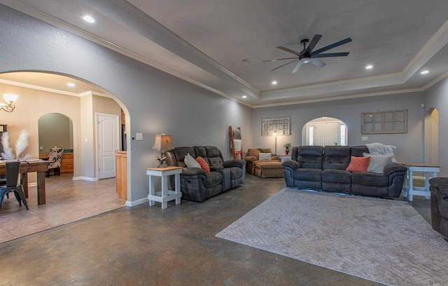 living room with a raised ceiling, crown molding, and ceiling fan