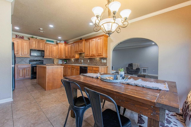 kitchen with a kitchen island, decorative light fixtures, light tile patterned floors, black appliances, and crown molding