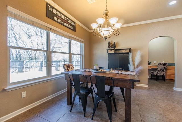 dining room with tile patterned flooring, ornamental molding, plenty of natural light, and a notable chandelier